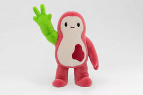 Kiki raising her green arm with two enlarged fingers sticking upwards.
