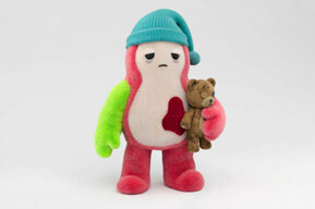 Kiki wearing a blue sleep cap and a tired facial expression while holding a small teddy bear.